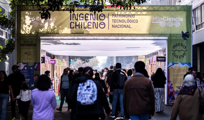 Una multitud de personas recorre una calle Morandé entre Agustinas y Huérfanos bajo un arco con una gráfica de la muestra del Ministerio de Ciencia en el marco del Día de los Patrimonios. 2026